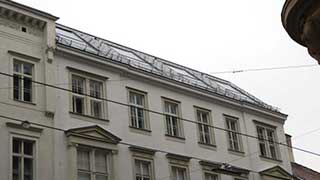Seitenansicht auf zwei Obergeschoße eines Gründerzeithauses mit Steildach und großen Dachfenstern