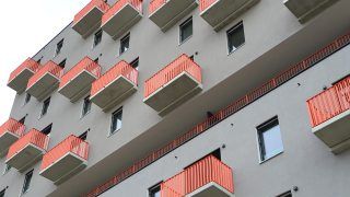 Detailansicht auf Gebäude mit grauer Fassade und Balkonen mit Geländern in orange