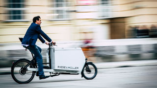 Takım elbiseli bir adam yük taşıyabilen bisiklete binmiş 