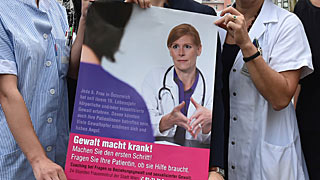 Aile içi şiddeti konu alan bir afiş. Afişte doktor kadın hastasıyla konuşuyor.