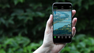 Hand hält Smartphone mit Aufschrift "Sehenswertes auf der Donauinsel" auf dem Bildschirm