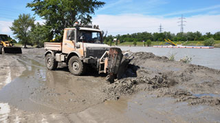 Schlamm am Ufer nach dem Hochwasser 2013 wird mit schwerem Gerät beseitigt