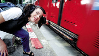 eine Frau mit Ohrenschutz neben einer Straßenbahn