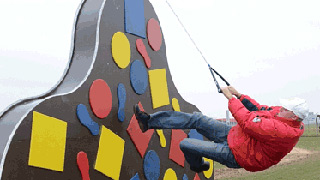 Ein Mann hngt an einem Seil an einer Kletterwand