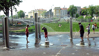Kinder spielen unter wasserspeienden Säulen