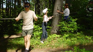 Kinder gehen an einem Seil durch den Wald