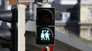 Green pedestrian traffic lights displaying two women who hold hands, a heart as symbol between them