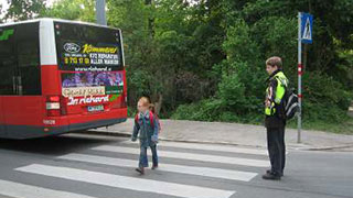Schulkind berquert Zebrastreifen bei Bushaltestelle Aspernallee, Schlerlotse sichert Strae