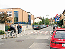 Peterlinigasse - Bereich Schule: durch eine Rampe erhhter, rot unterlegter Zebrastreifen, haltende und parkende Autos im Kreuzungsbereich