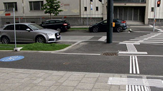 Kreuzungsbereich Maria-Rekker-Gasse - Favoritenstrae: Breite Staenkreuzung mit Haupt- und Nebenfahrbahn, Straenbahnschienen, Zebrastreifen und Fugngerampel