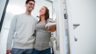 Ein junges Paar öffnet die Tür zu einer Wohnung.