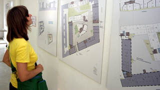 Frau betrachtet Gebäudeplan in einer Architekturausstellung